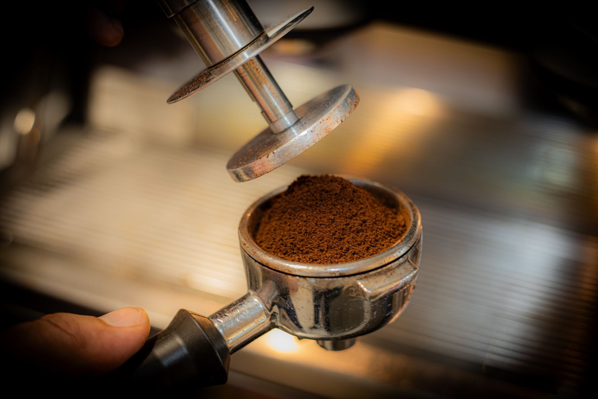 Close-up of ground coffee being tamped in a portafilter for espresso preparation.