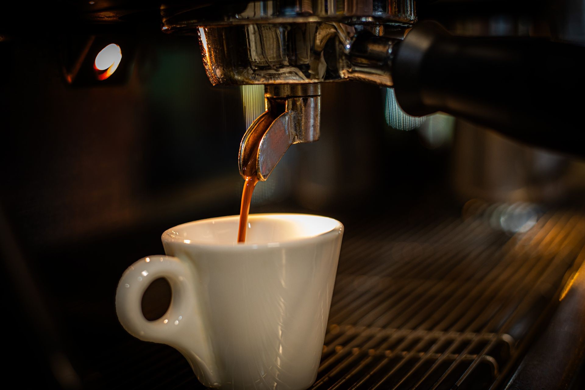 Espresso machine pouring fresh coffee into a white cup.